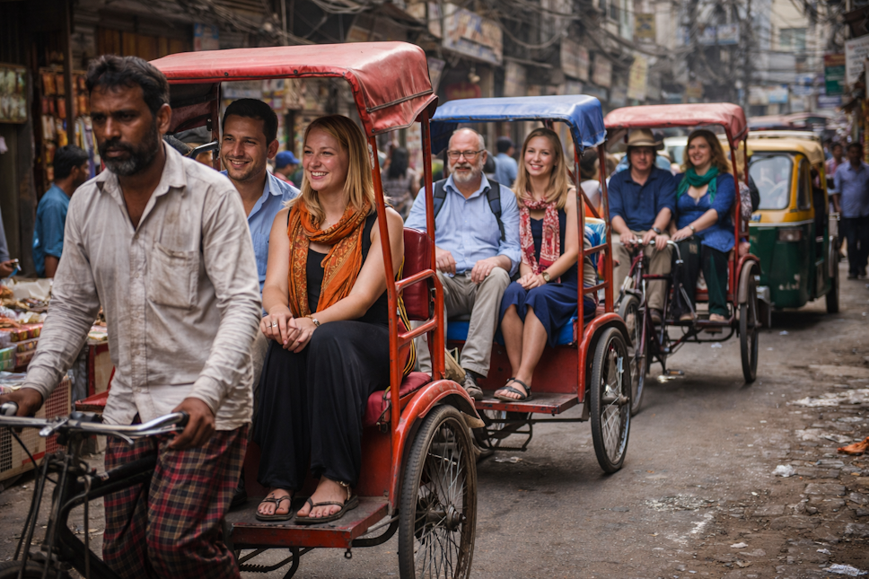 Foreign tourists enjoying a traditional rickshaw ride through the bustling lanes of Old Delhi during a guided heritage walk experience